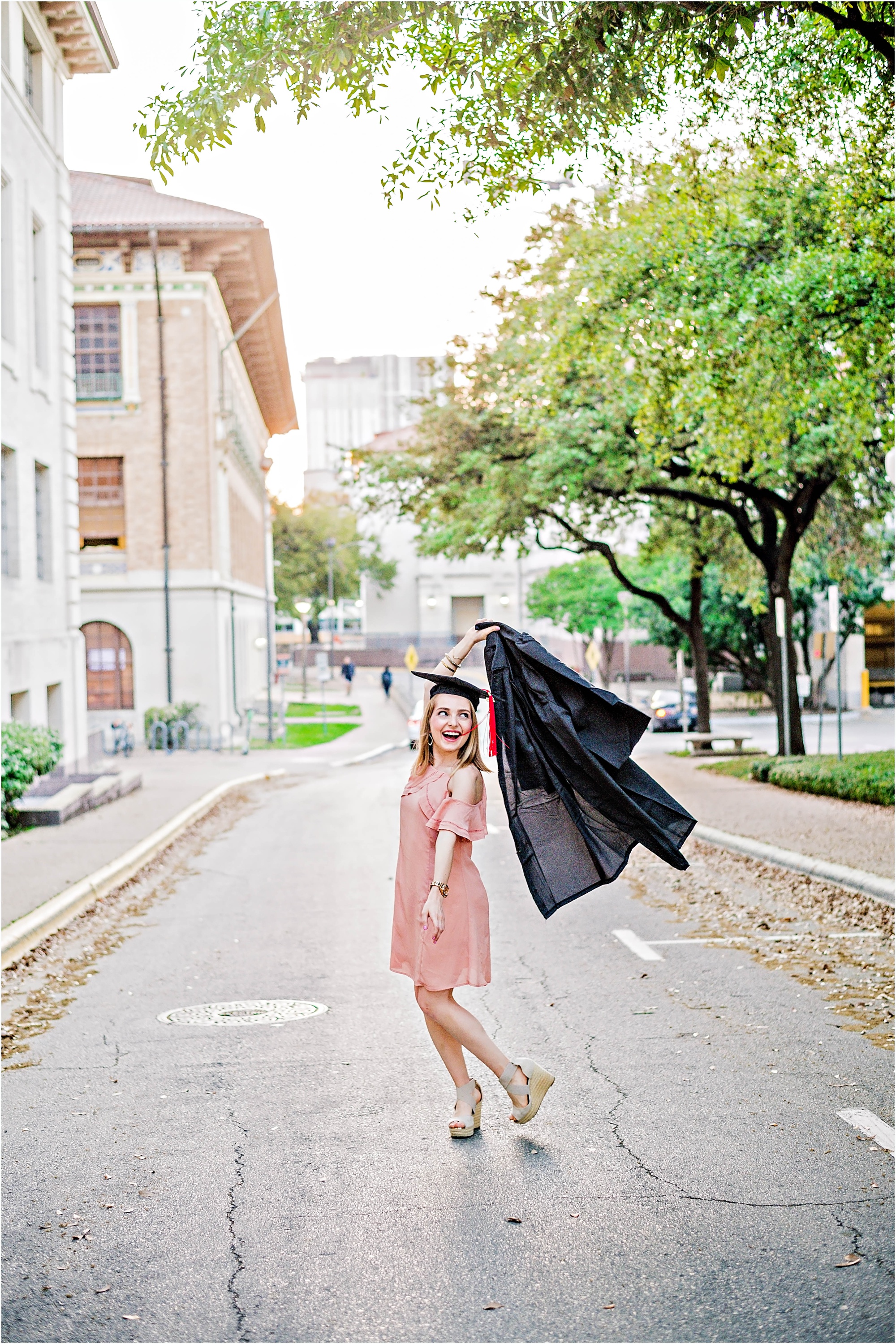 University of Texas Graduate Twirling in Street with Cap and Gown Natural Light Austin Texas Photographer Graduation Photoshoot