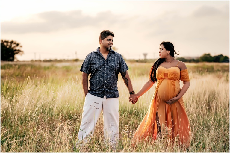 Couple in long field of grass during maternity photoshoot in Round Rock Texas by natural light portrait photographer