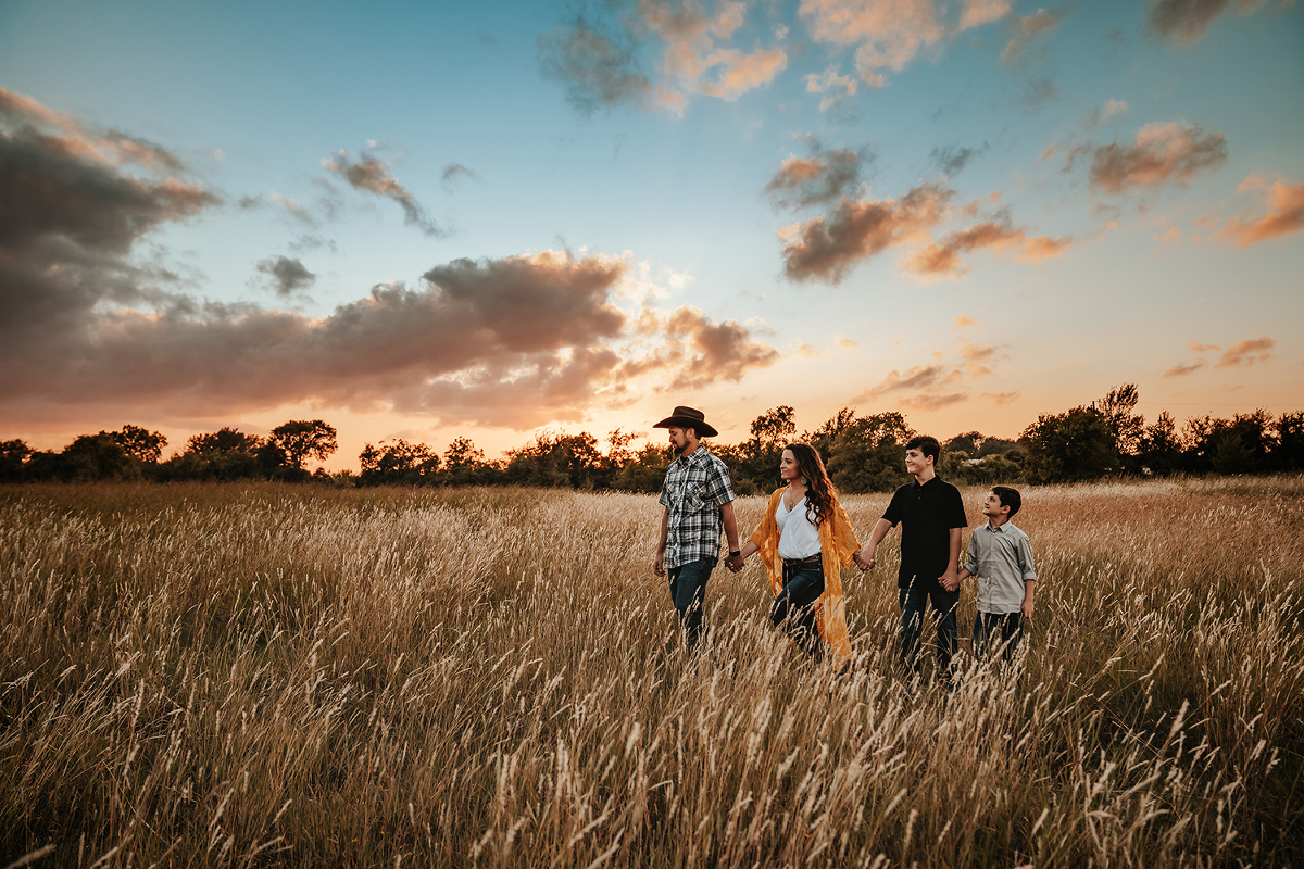 family photoshoot while walking through long grassy field in Round Rock Texas by natural light milestone photographer